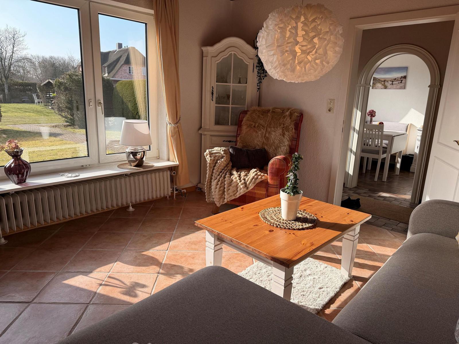 Wohnzimmer mit Sitzgelegenheiten, Tisch und Blick auf den Garten.