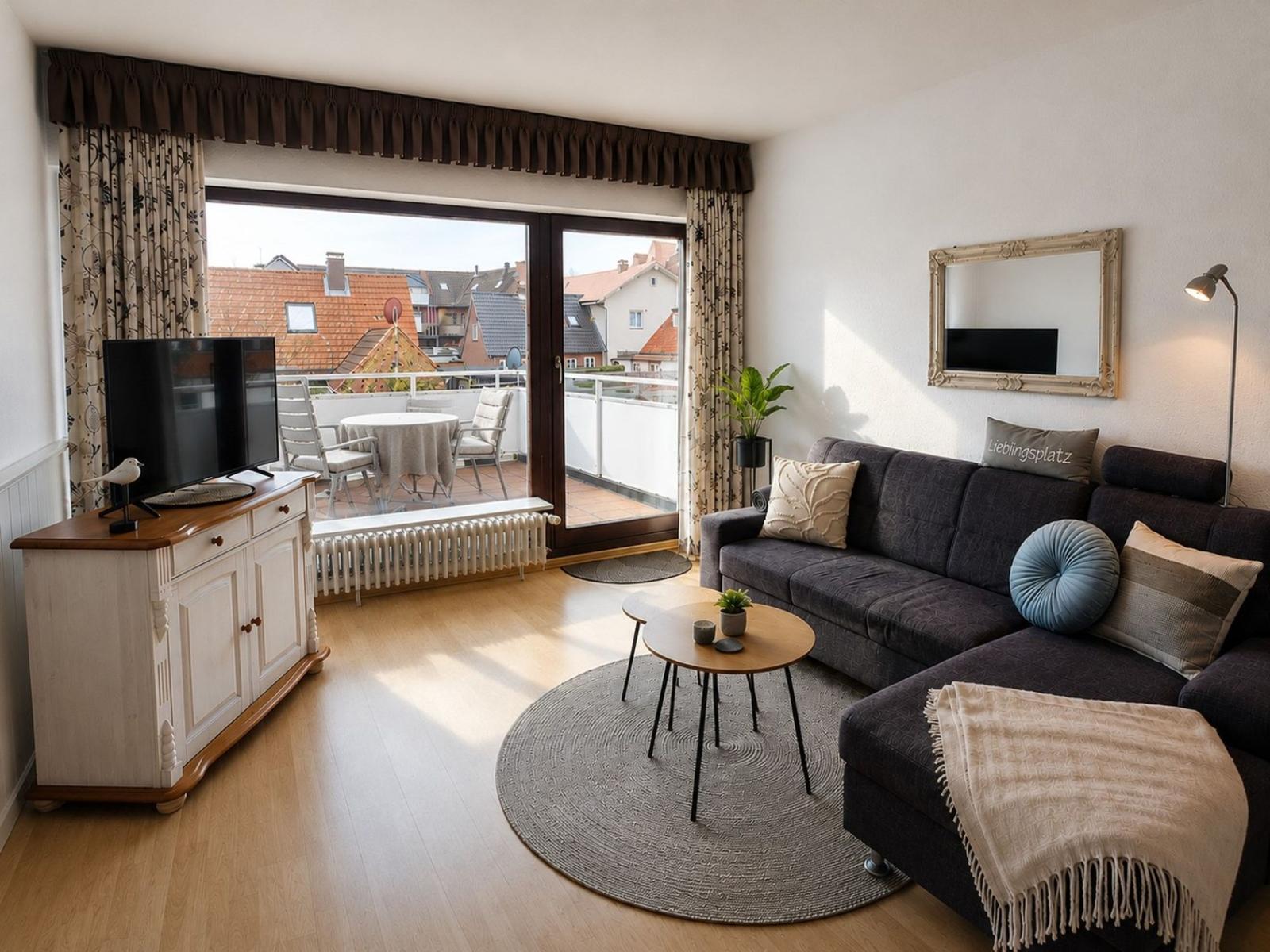 Wohnzimmer mit Sofa, Couchtisch und Balkon mit Sitzgelegenheiten.