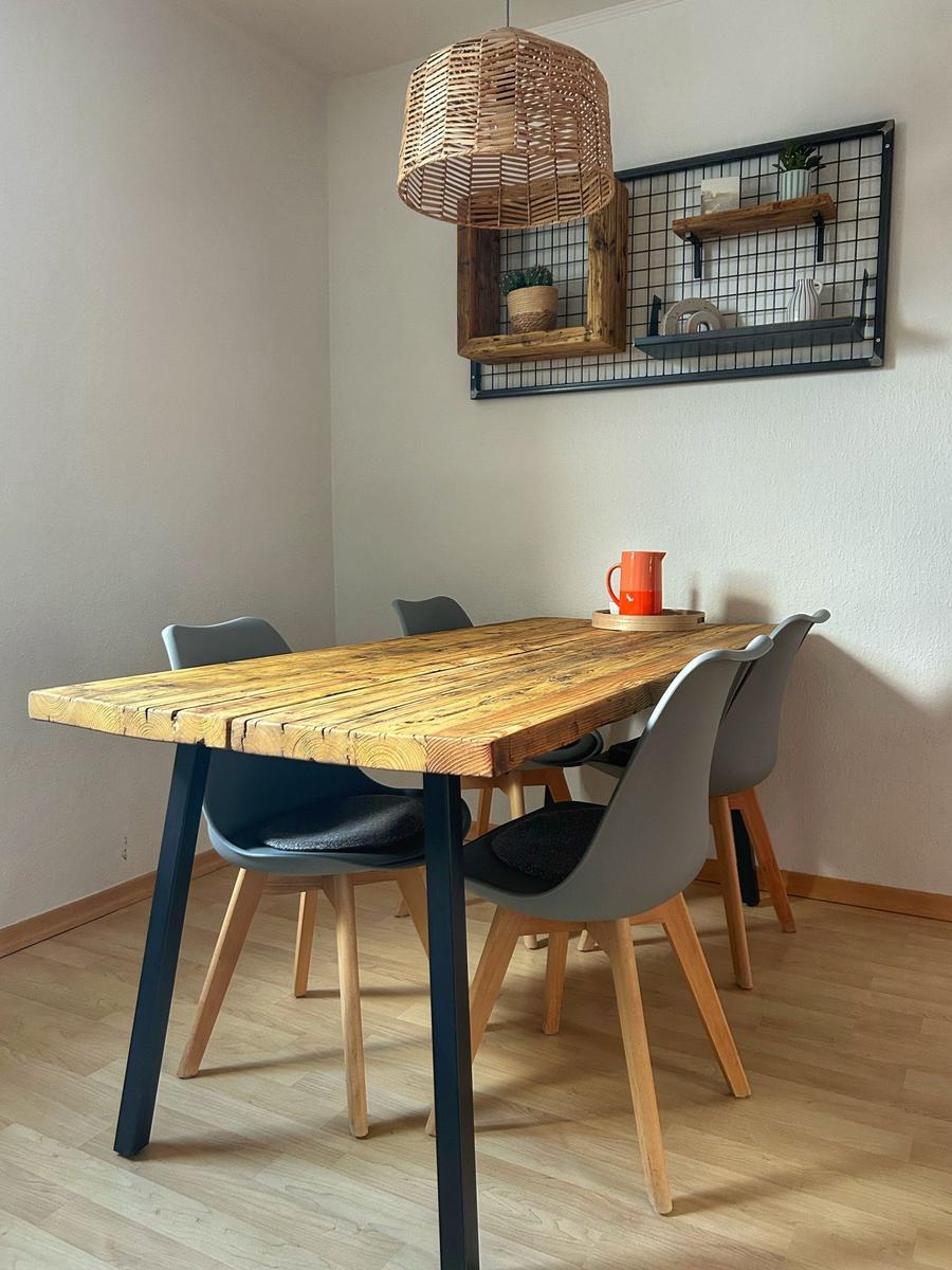 Holztisch mit vier Stühlen und Wickerlampe an der Wand