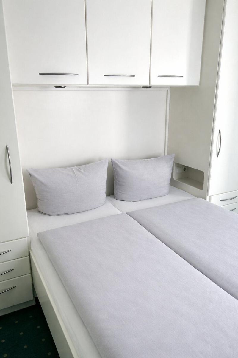 Bedroom with double bed, white wardrobes, and pillows.