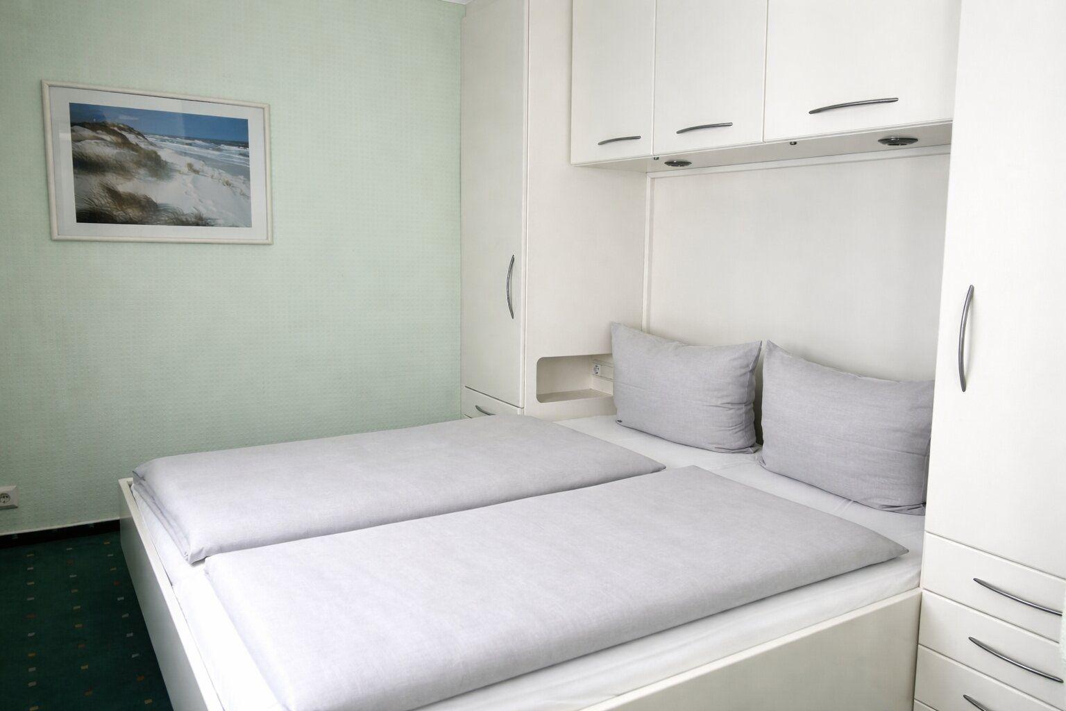 Bedroom with double bed, white wardrobes, and wall picture