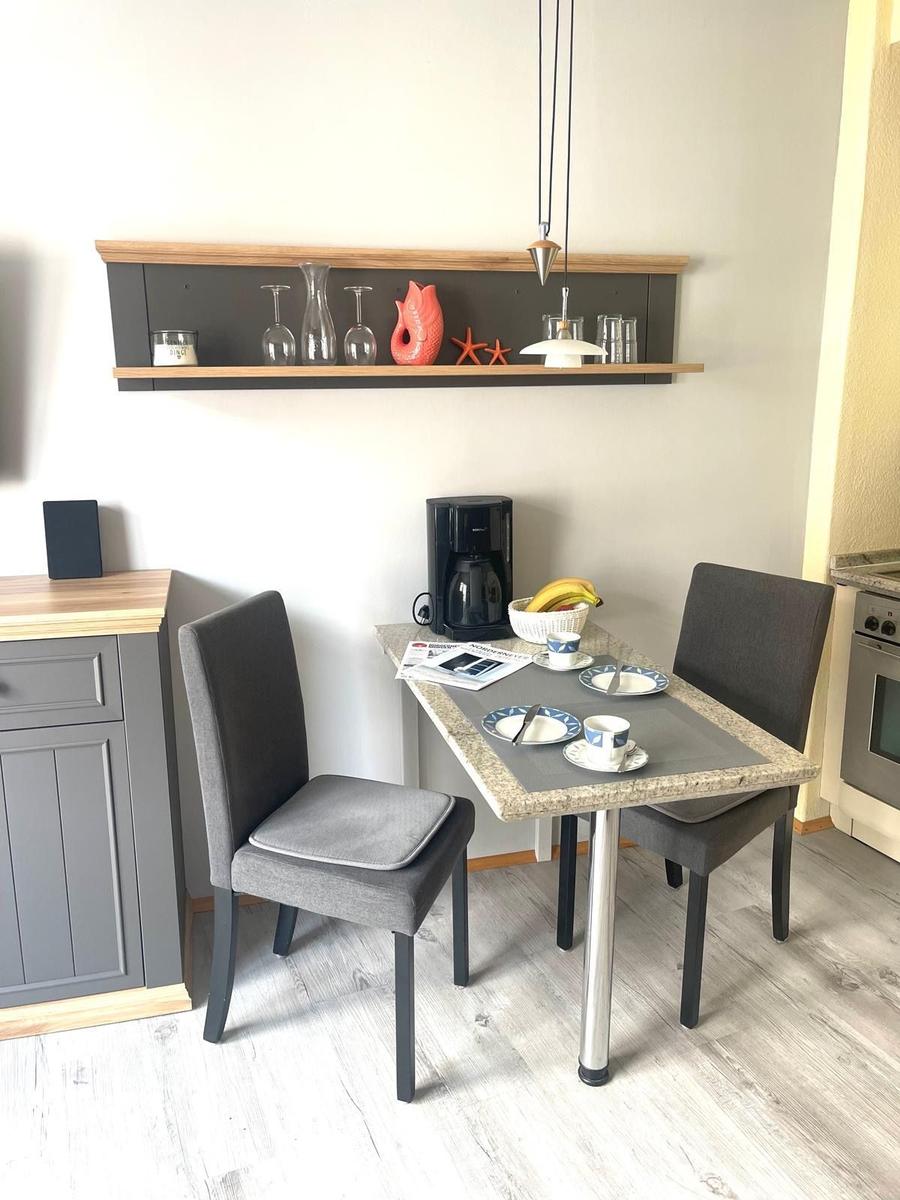 Esstisch mit zwei Stühlen, Kaffeemaschine und Dekoration an der Wand.
