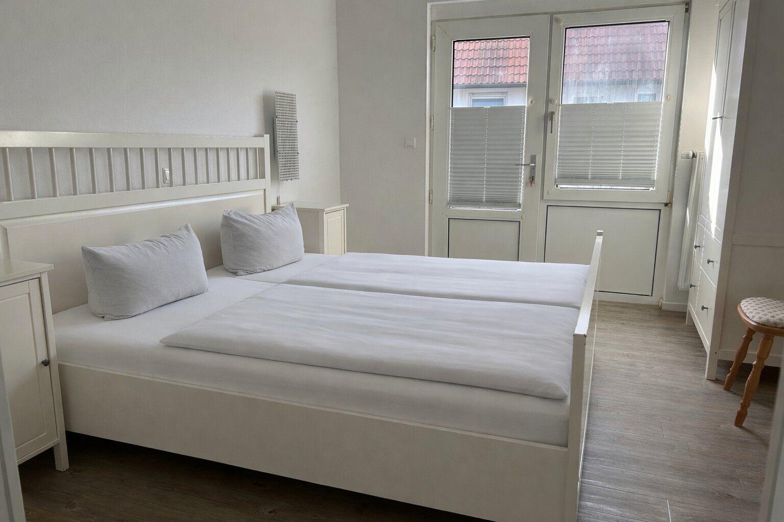 Schlafzimmer mit Doppelbett, Schrank und Fenster zur Außenseite.
