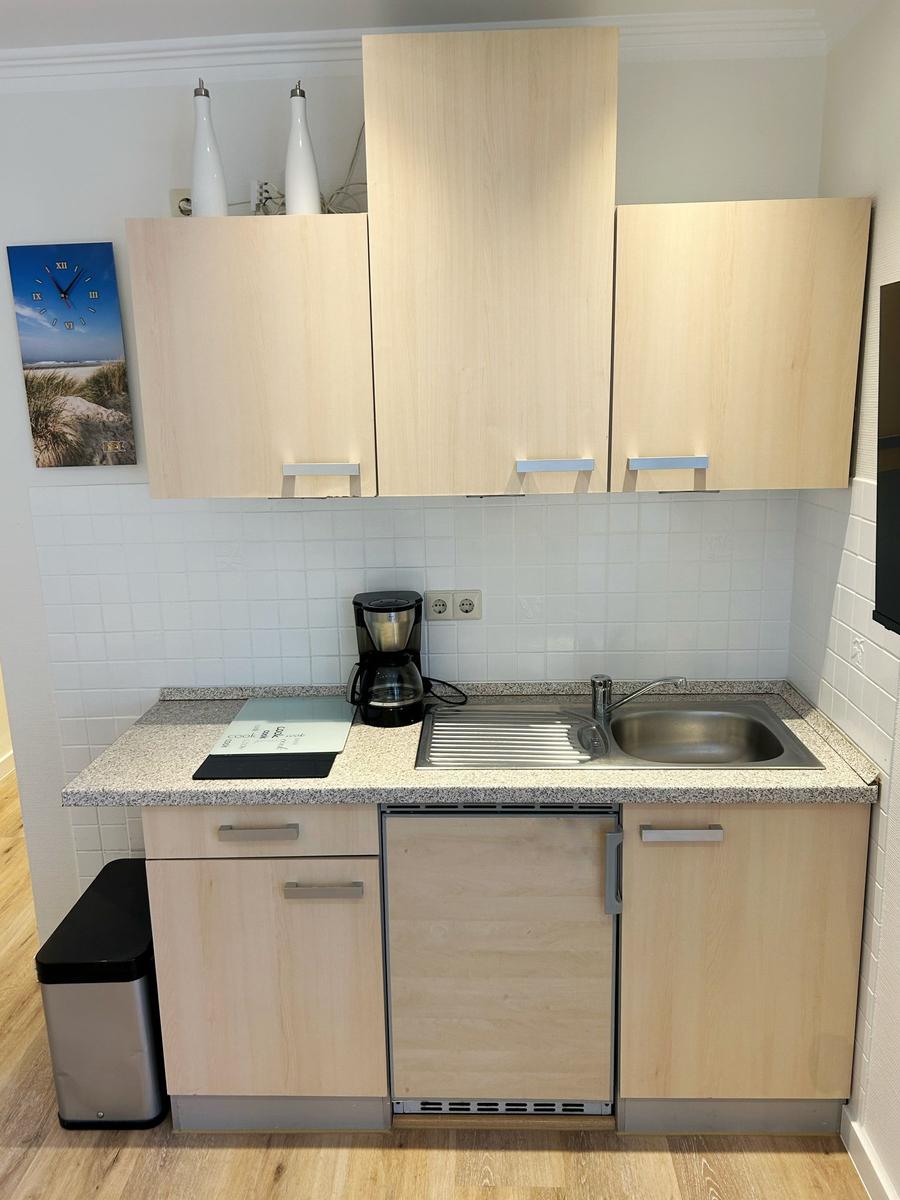 Küche mit Holzschränken, Spüle und Kaffeemaschine