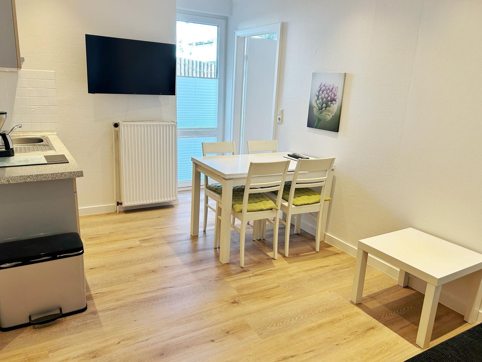 Küche mit Esstisch, Fernseher und Heizung. Holzfußboden und Wandbild.