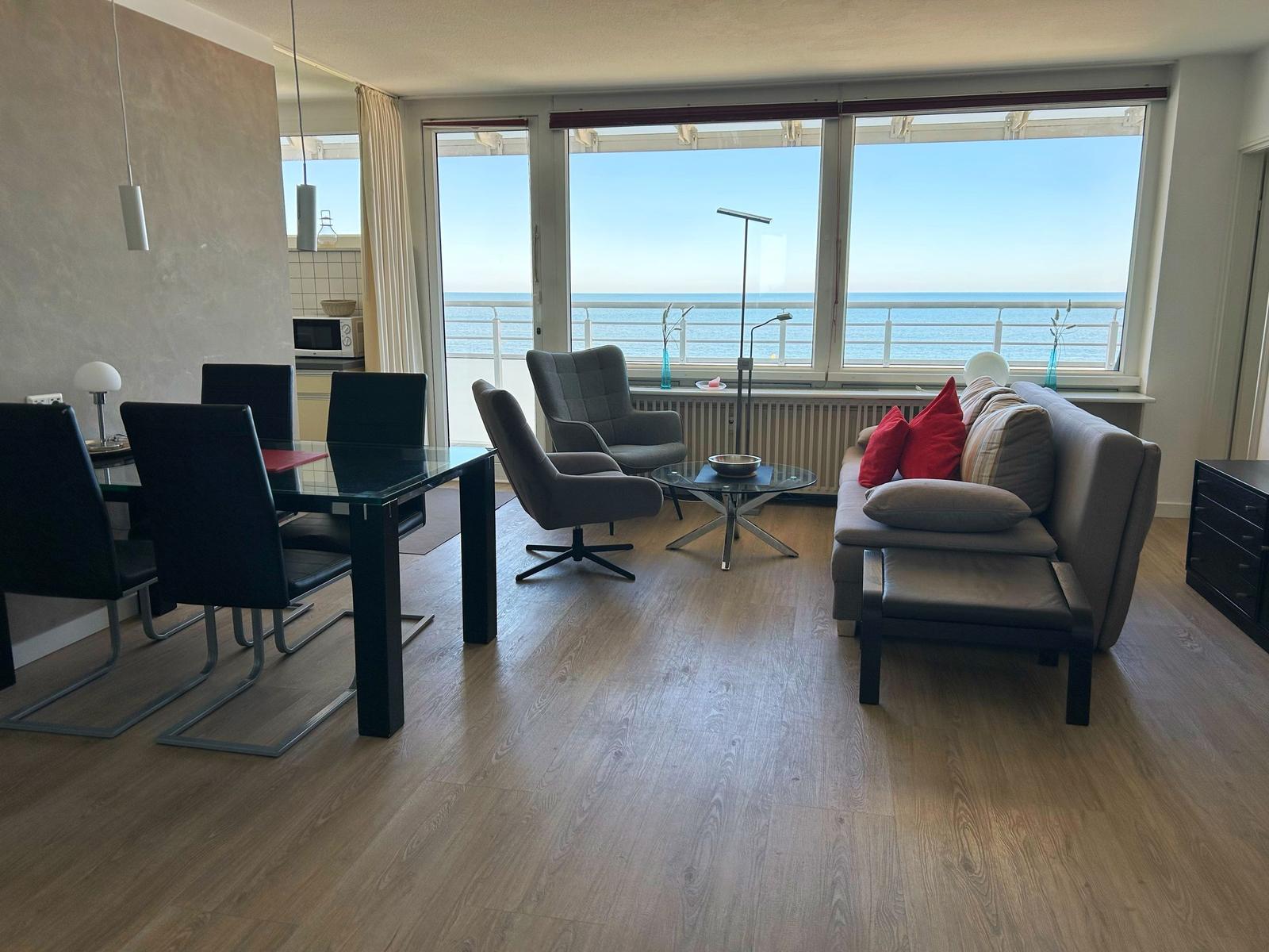 Wohnzimmer mit Essbereich und Meerblick durch große Fenster.