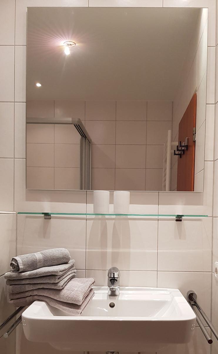 Bad mit Spiegel, Waschbecken und Handtüchern