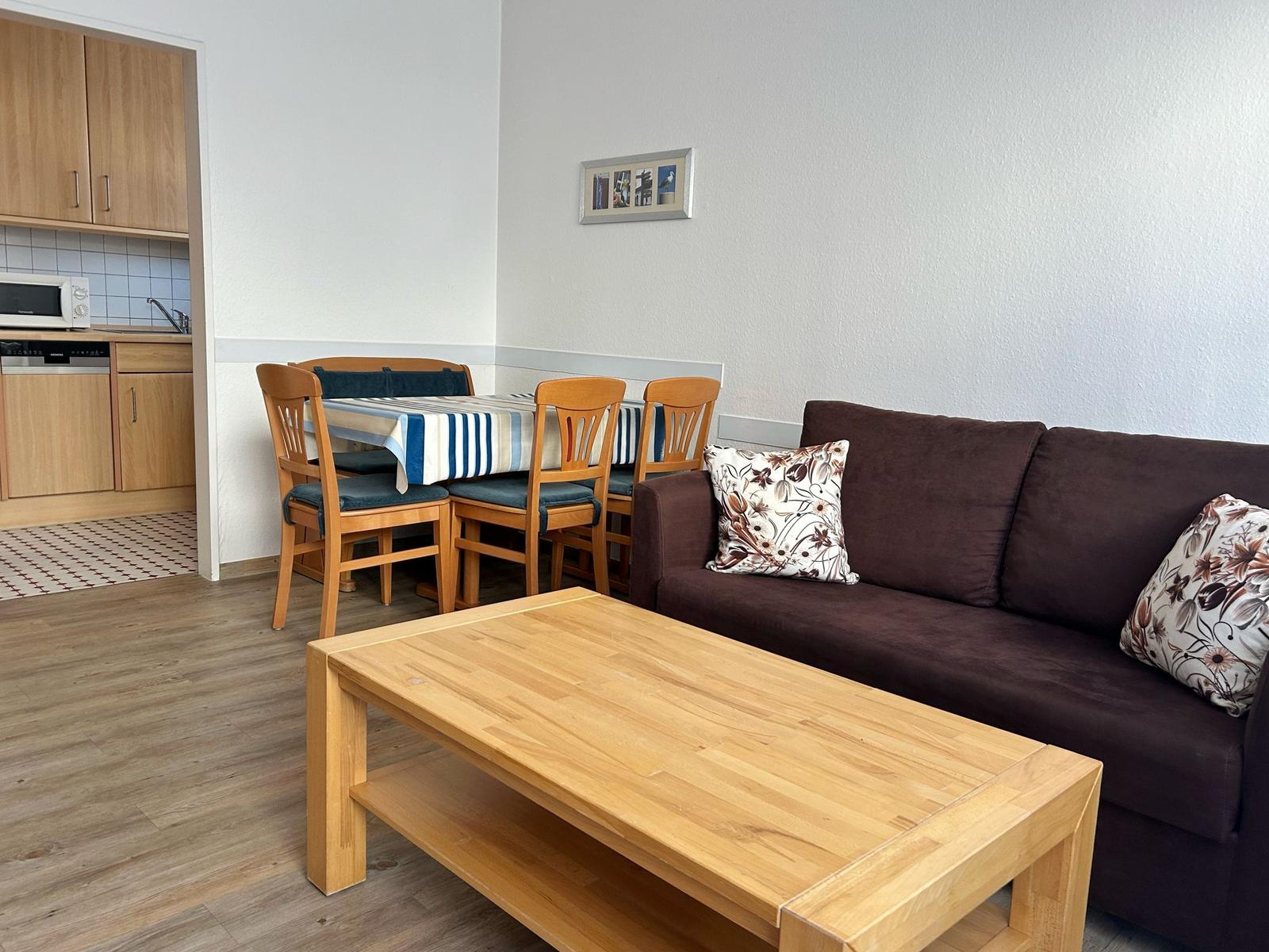 Wohnzimmer mit Sofa, Esstisch und Küchenbereich.