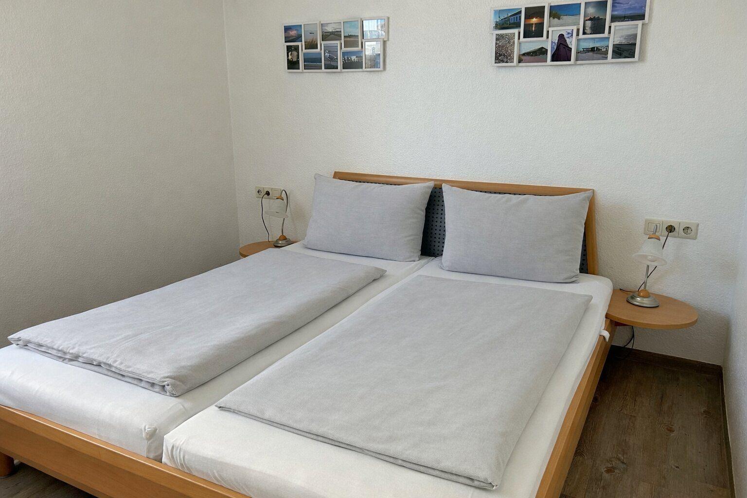 Doppelbett mit zwei Kissen und zwei Nachttischen mit Lampen.