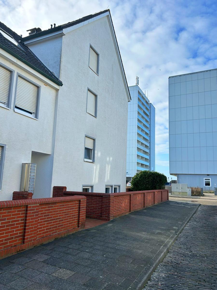 Wohnhaus mit rotem Ziegelzaun und modernen Hochhäusern im Hintergrund.
