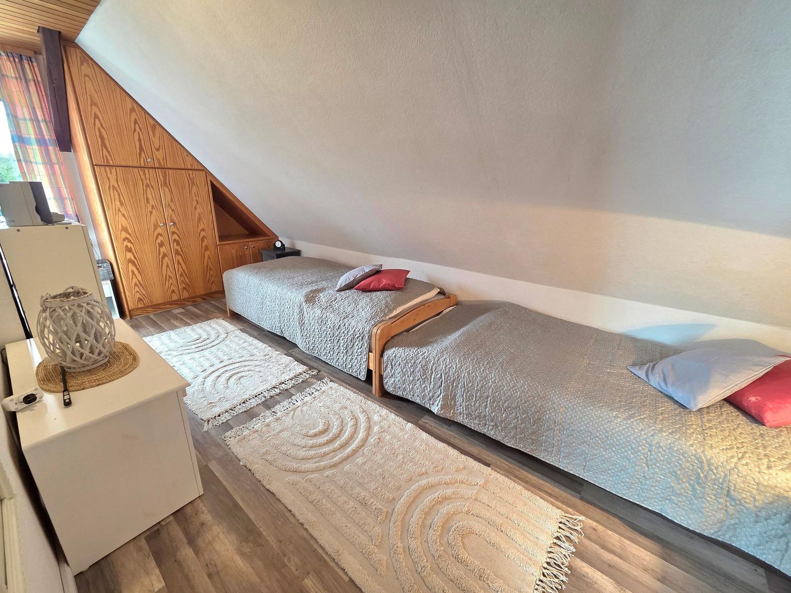 Zwei Schlafplätze mit Matratzen und Kissen unter schräger Decke.