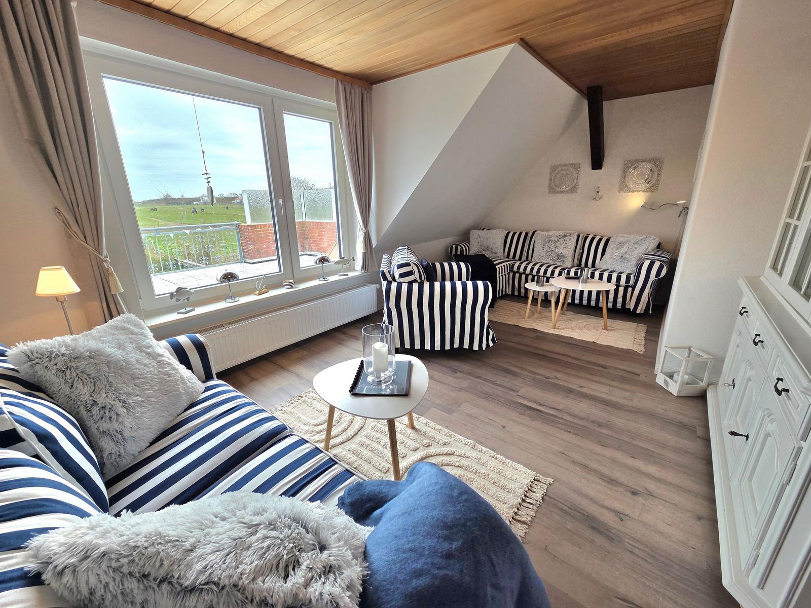 Wohnzimmer mit Streifensofa, Holzboden und großem Fenster mit Blick.