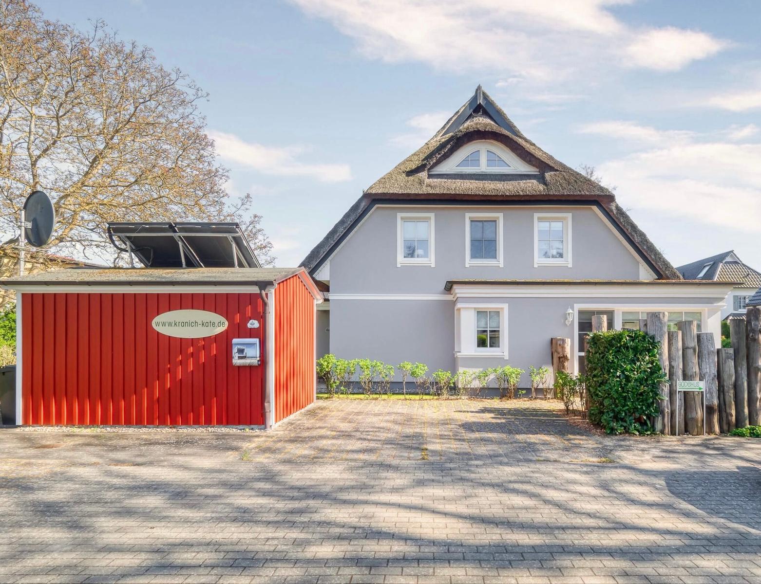 House with thatched roof, red extension, and paved courtyard.