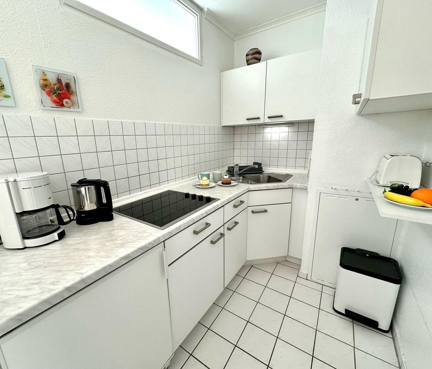 Küche mit weißen Schränken, Marmorarbeitsplatte und Kühlschrank.