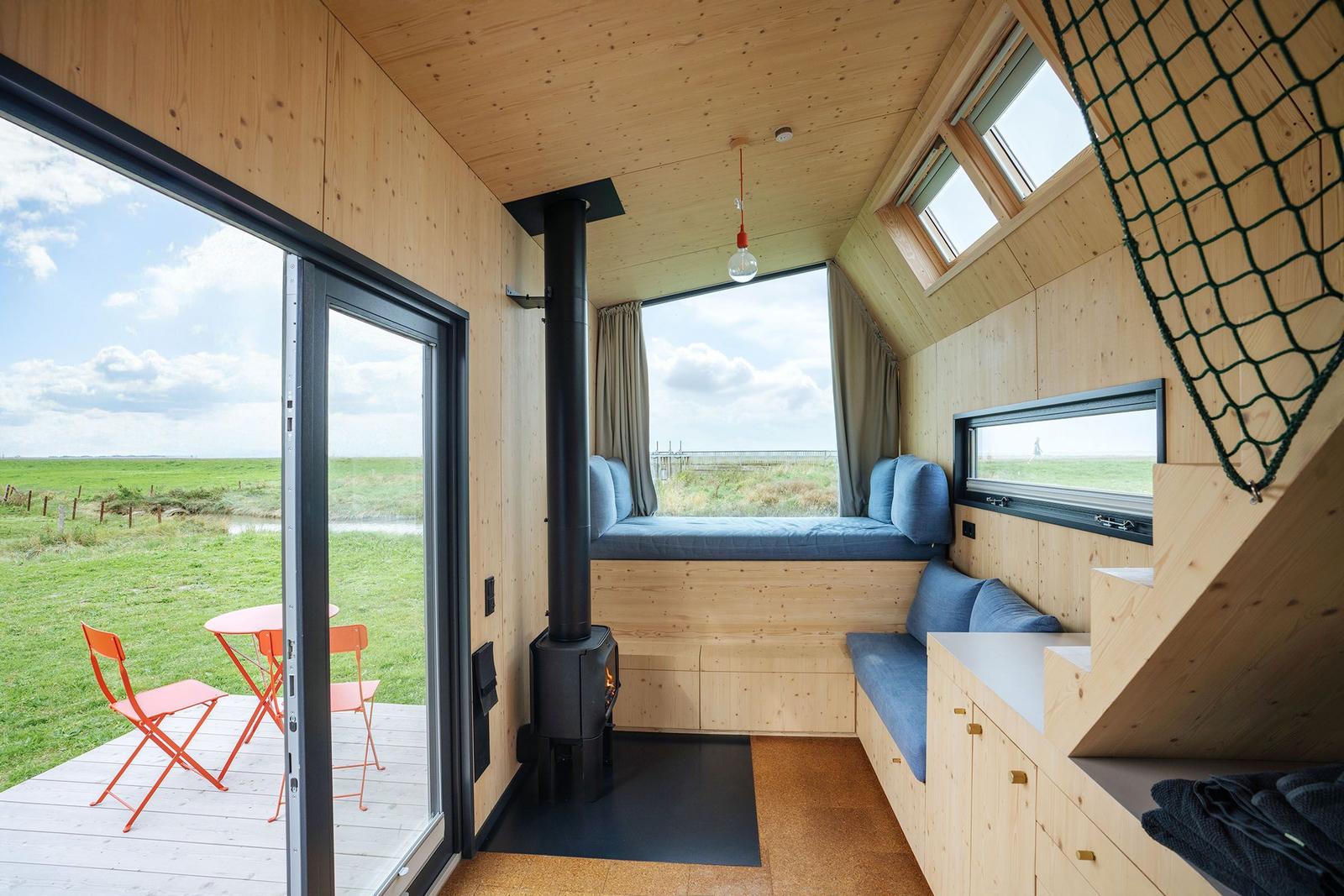 Holzhaus mit Fensterbank, Kamin und Terrasse mit orangefarbenem Tisch und Stühlen.