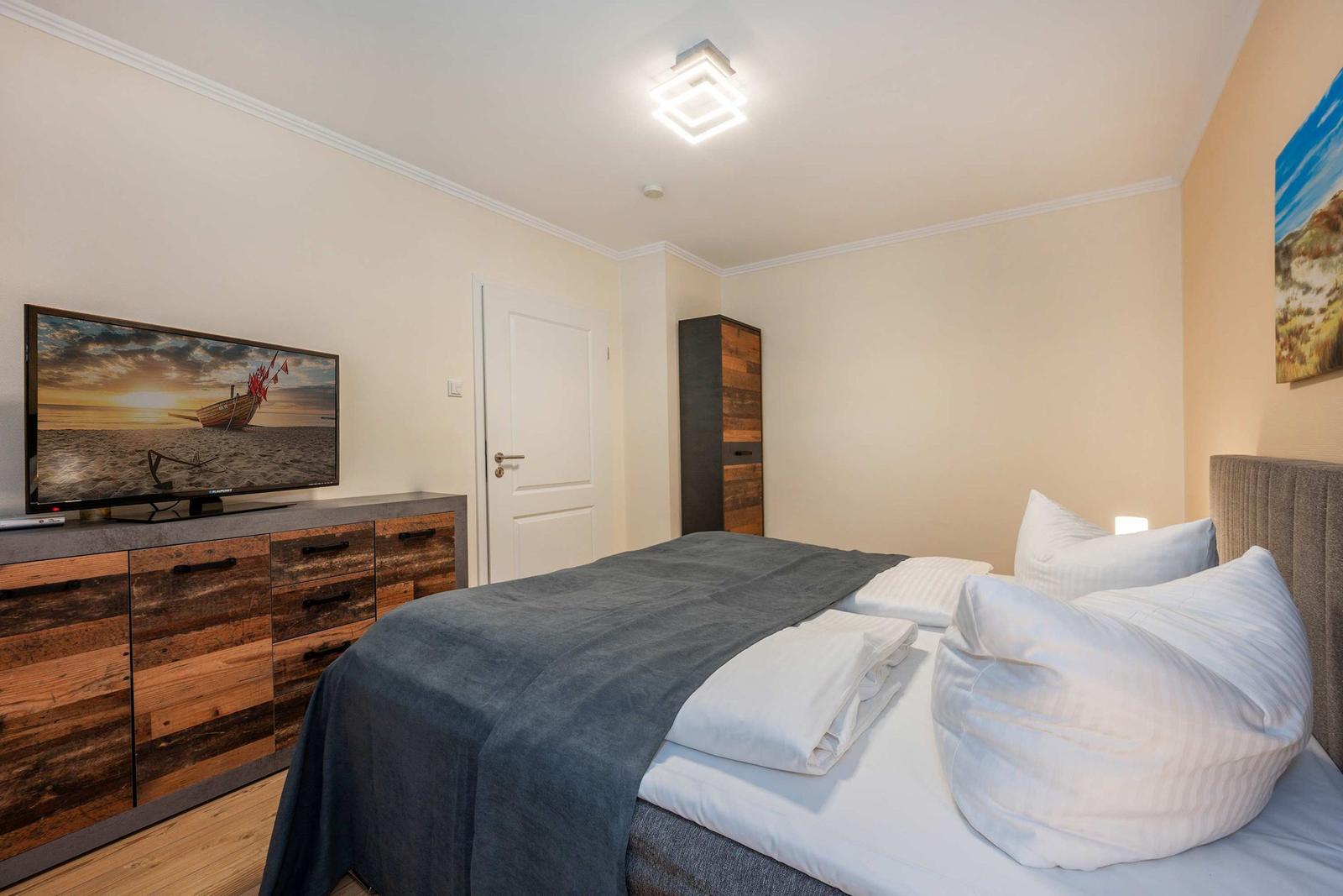 Schlafzimmer mit Bett, Fernseher und Kleiderschrank.