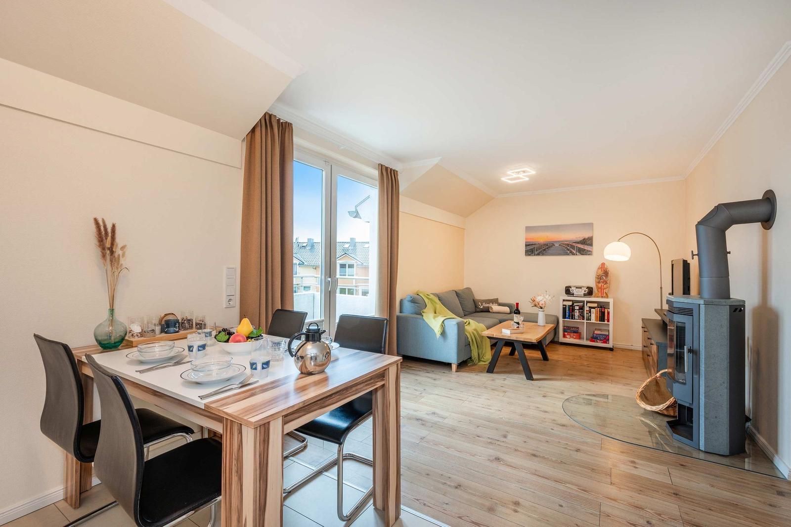 Wohn- und Essbereich mit Holzboden, Sofa, Esstisch und Kaminofen.