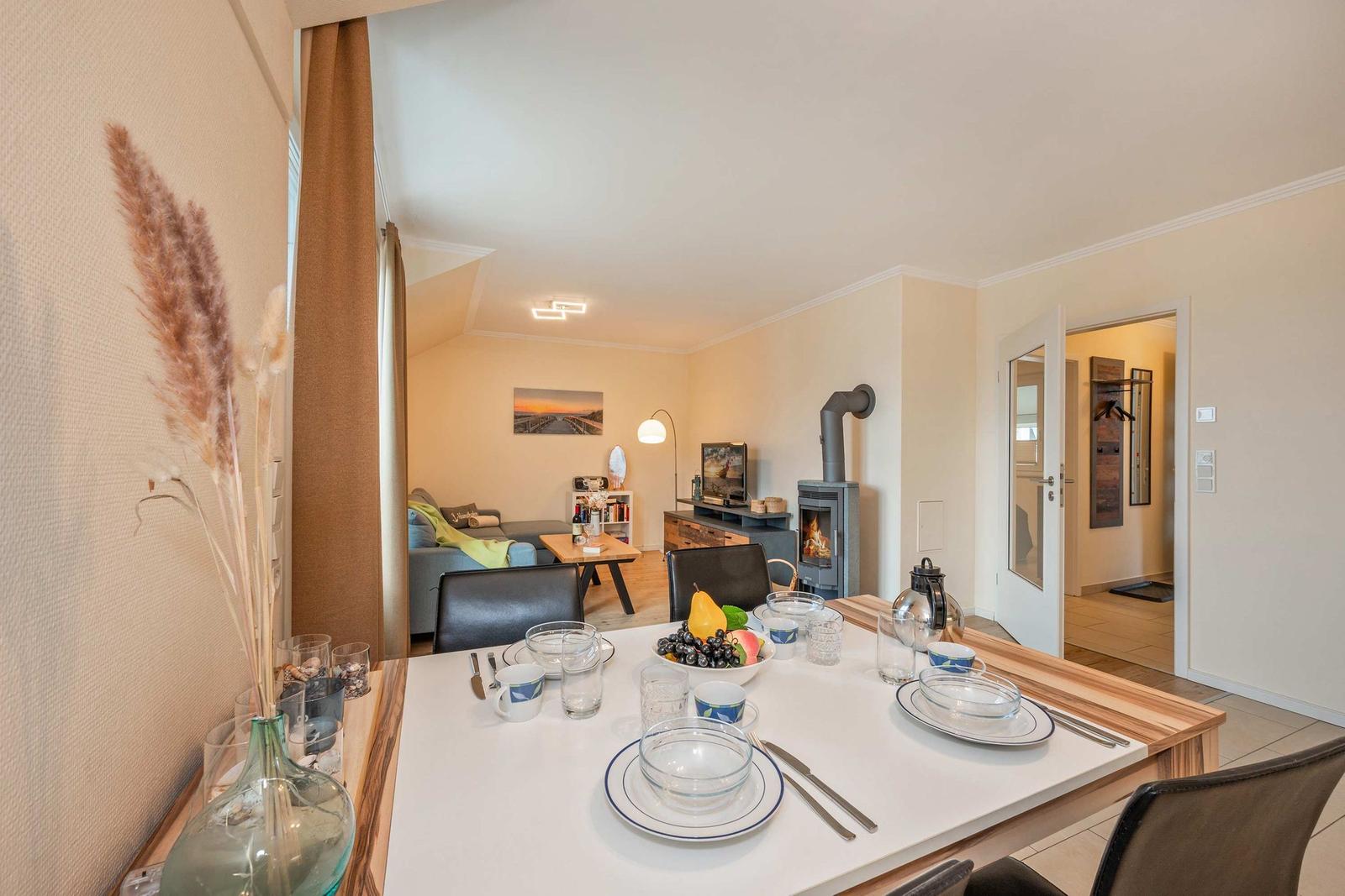Esstisch mit Geschirr, im Hintergrund Wohnzimmer mit Kamin und Sofa.