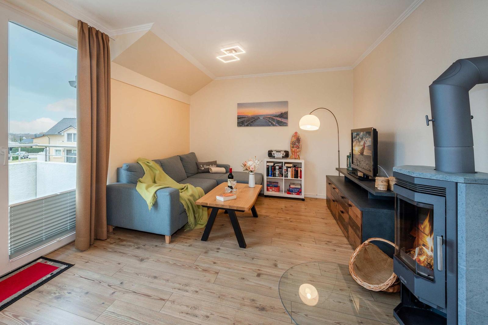 Wohnzimmer mit Sofa, Kamin und Terrassentür.