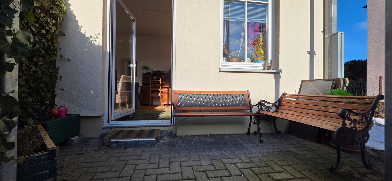 Terrace with two benches, entrance door, and view into the house.