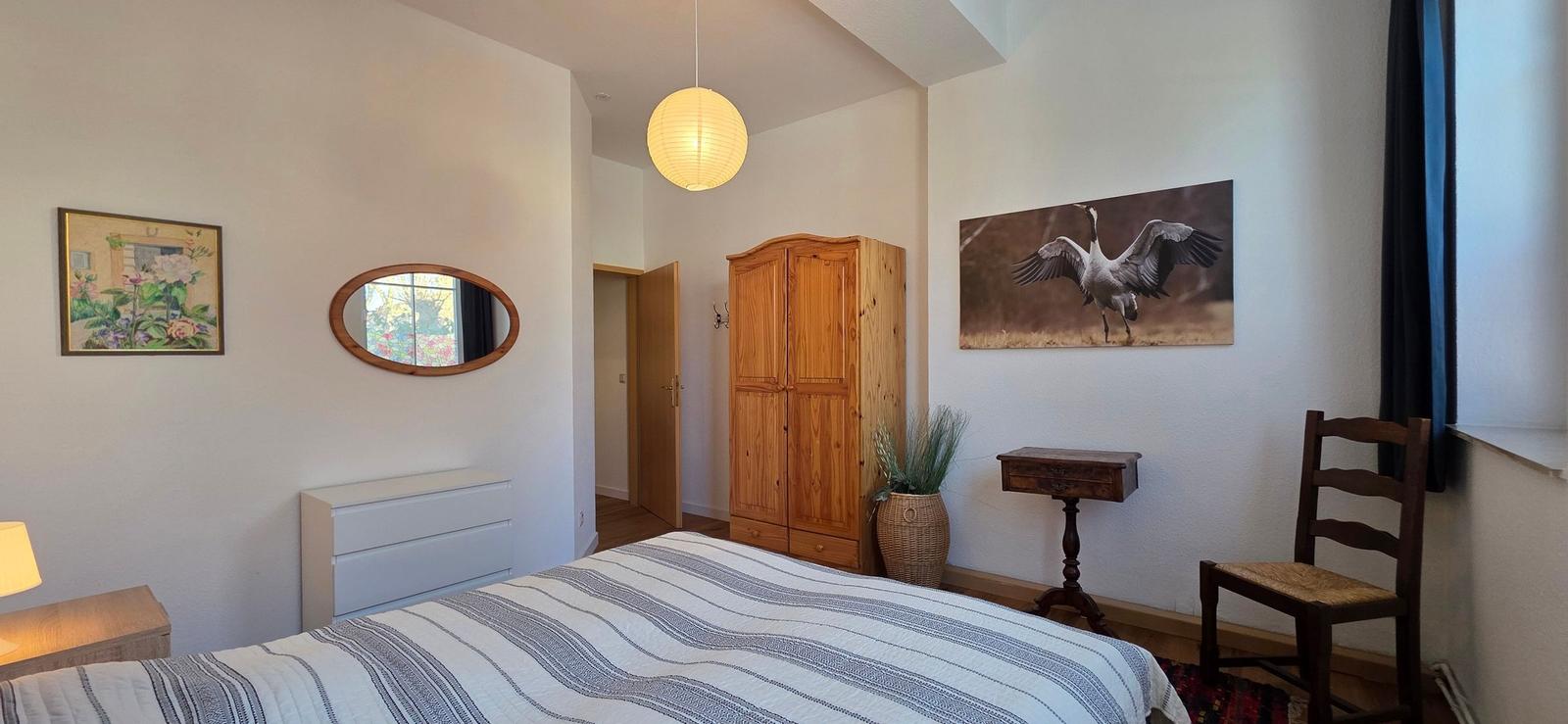 Bedroom with bed, wooden wardrobe, and wall picture of a crane.