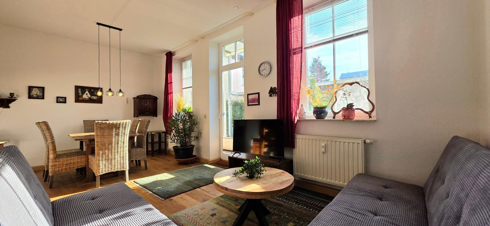 Living and dining area with sofa, table, chairs, and windows.