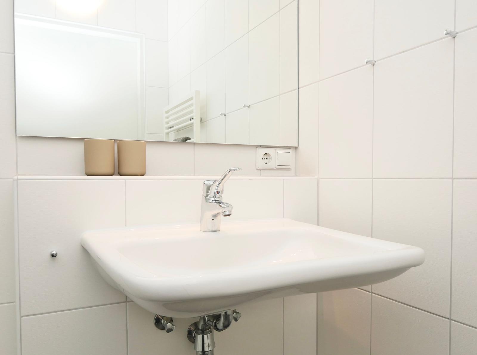 Waschbecken mit Spiegel und zwei beige Flaschen