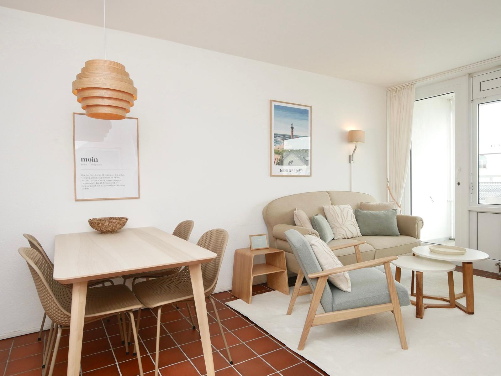 Wohn- und Essbereich mit Sofa, Stühlen, Tisch und Wandbildern.