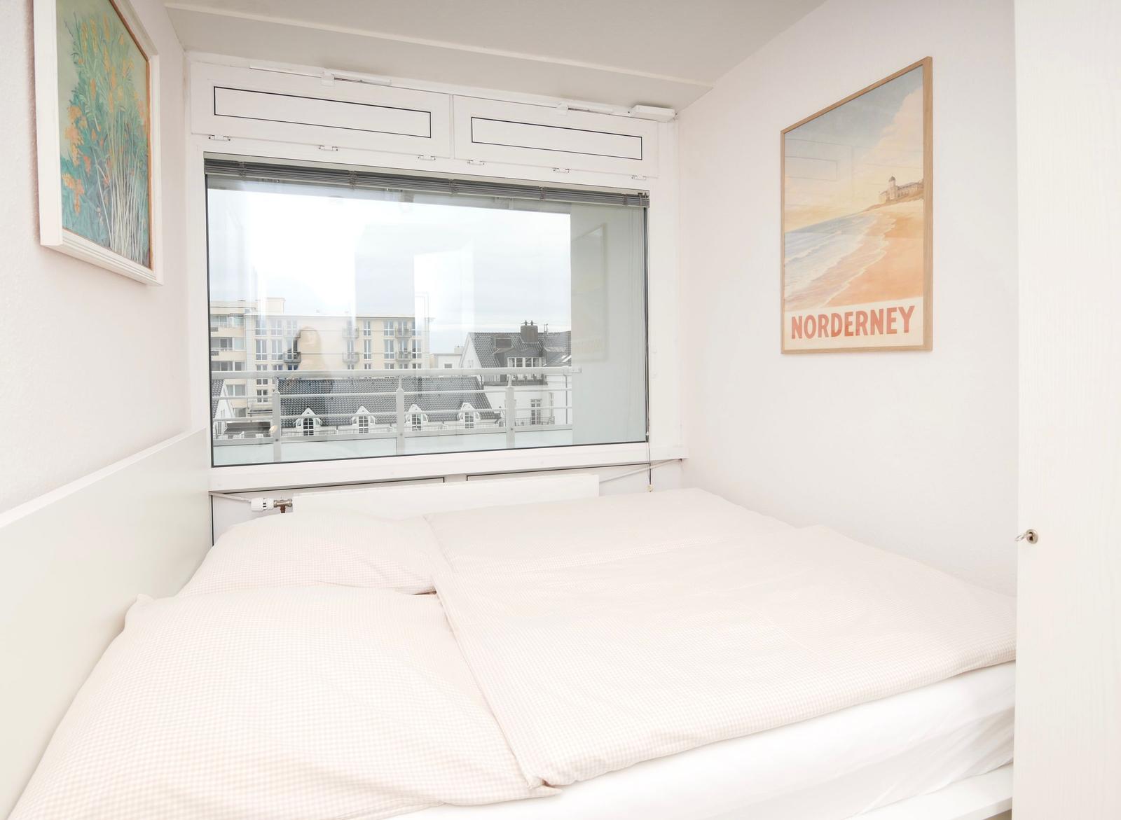 Schlafzimmer mit Bett, Fenster und Wandbild Norderney.