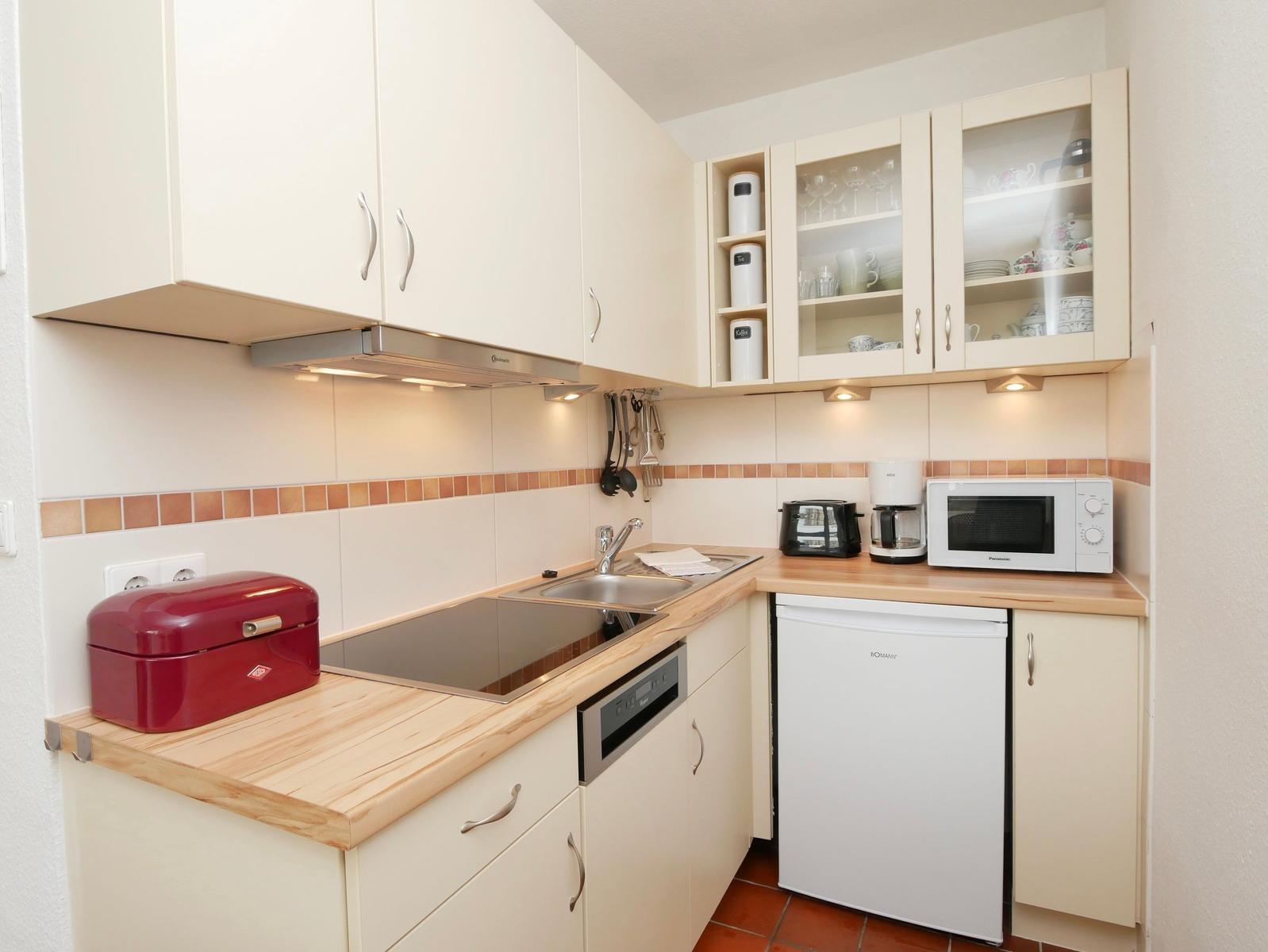 Küche mit Holz Arbeitsplatte, weißen Schränken und integriertem Kühlschrank.