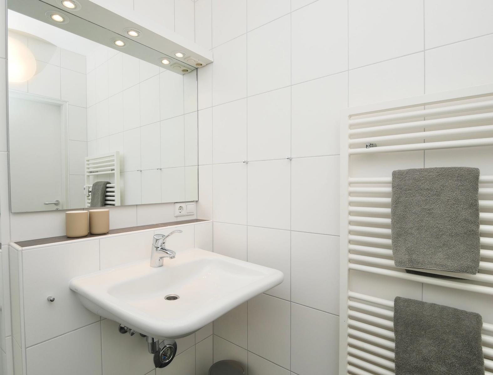 Badezimmer mit Waschbecken, Spiegel und Handtuchhalter.