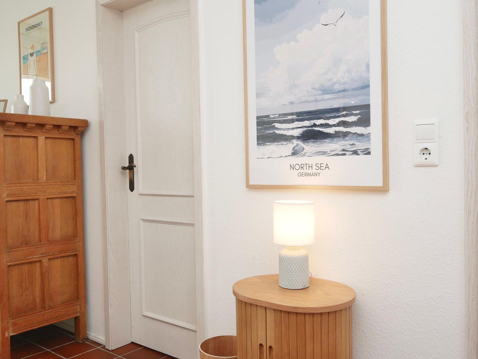 Eingangsbereich mit Holzschrank, Tür und Wandbild der Nordsee.