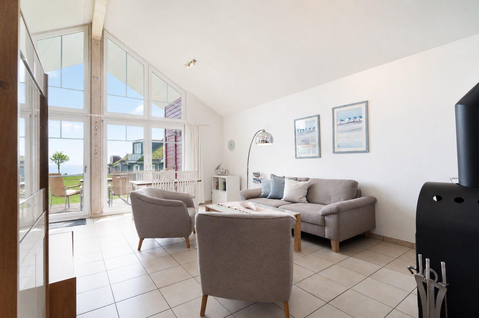 Living room with sofa, armchairs, and large window to terrace