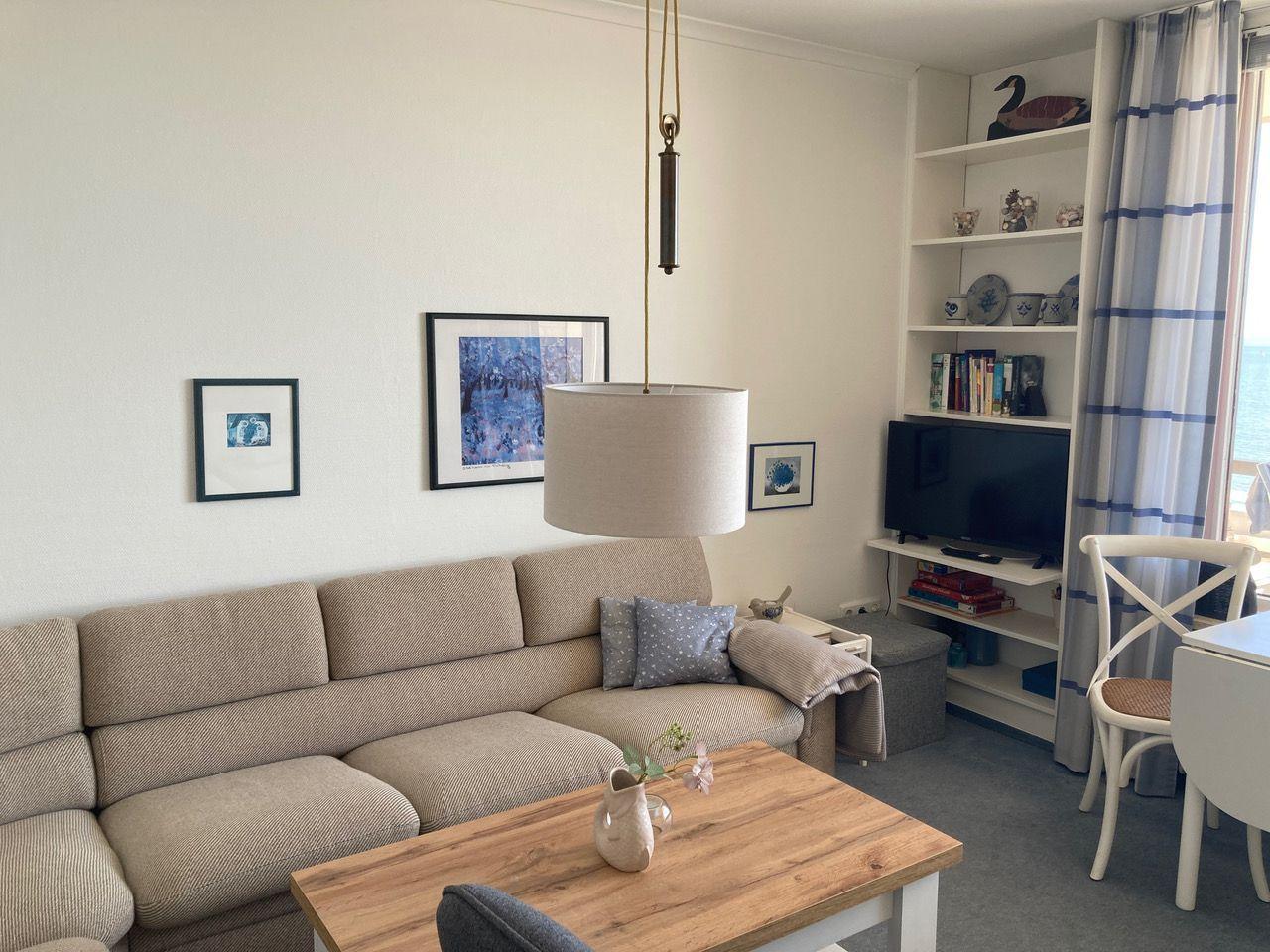 Living room with sofa, table, TV, and sea view.