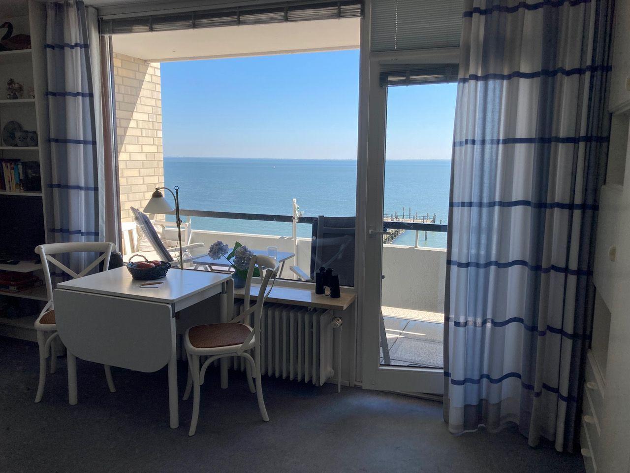 Room with sea view, table, chairs, and balcony with lounge chairs.