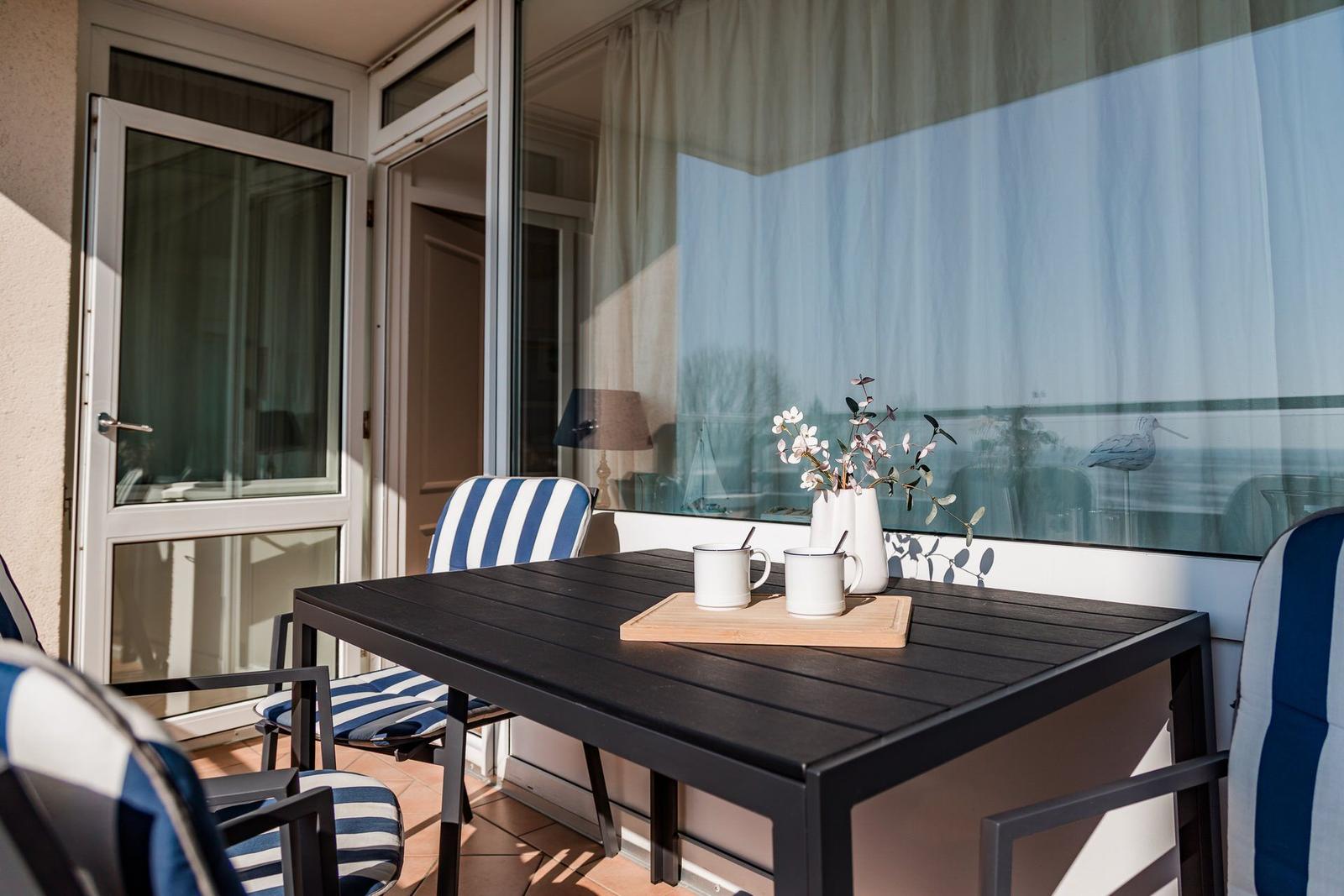 Terrace with table, chairs, and vase. Entrance to the apartment.