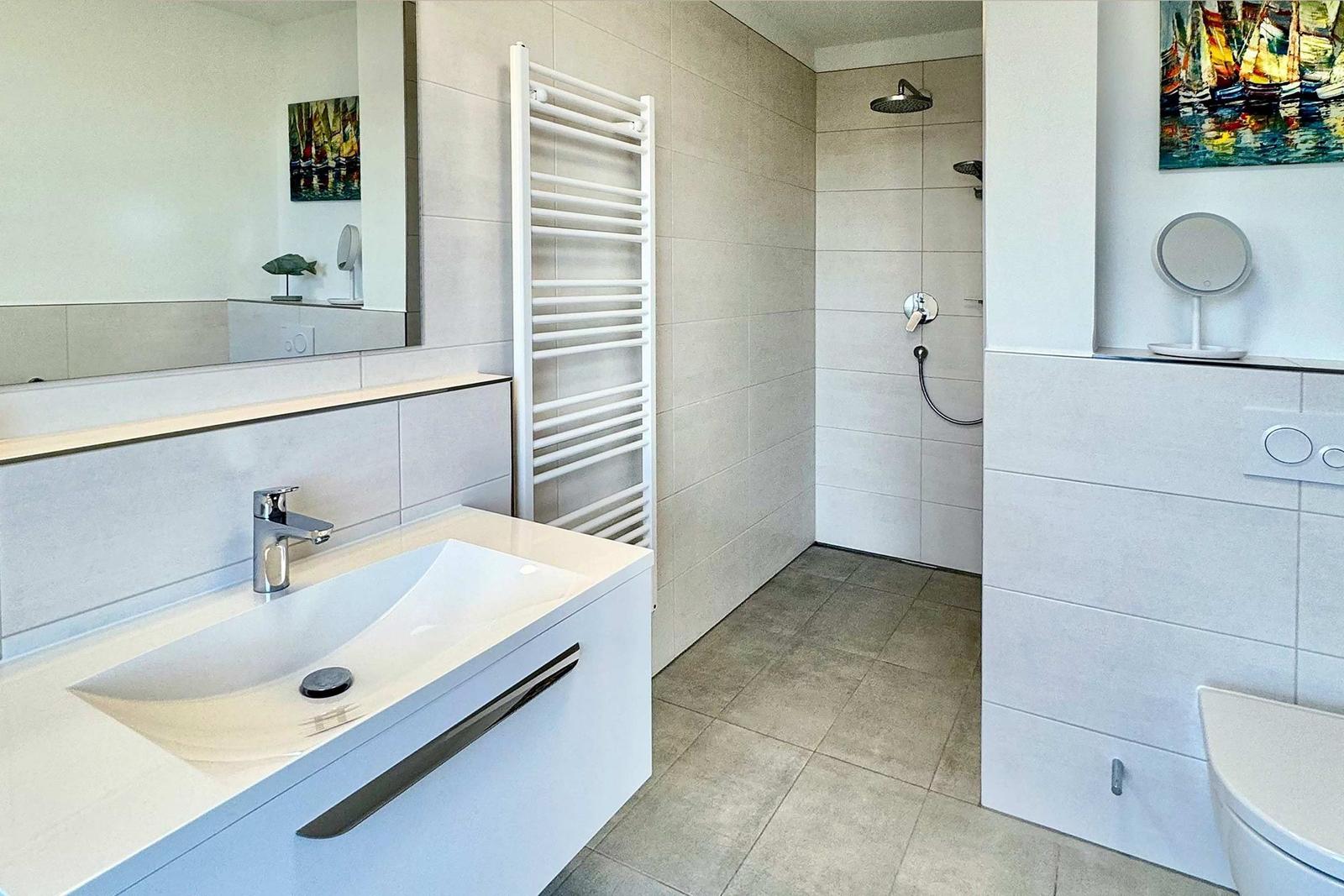 Badezimmer mit Dusche, Waschbecken und Heizkörper.