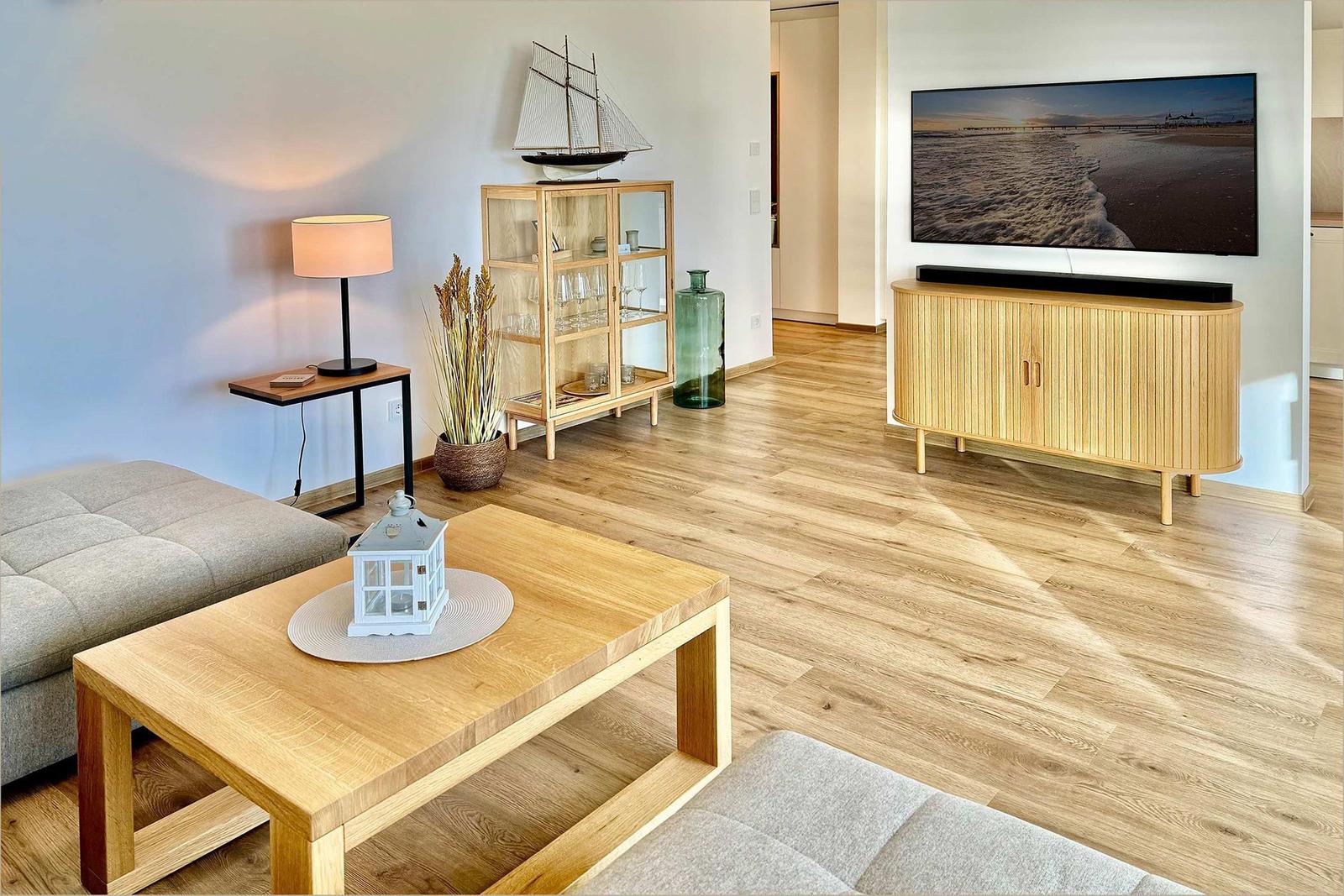Wohnzimmer mit Holzboden, Sofa, Tisch und Fernseher.