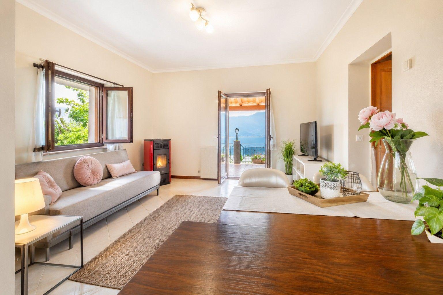 Wohnzimmer mit Sofa, Kamin und Blick auf das Meer.