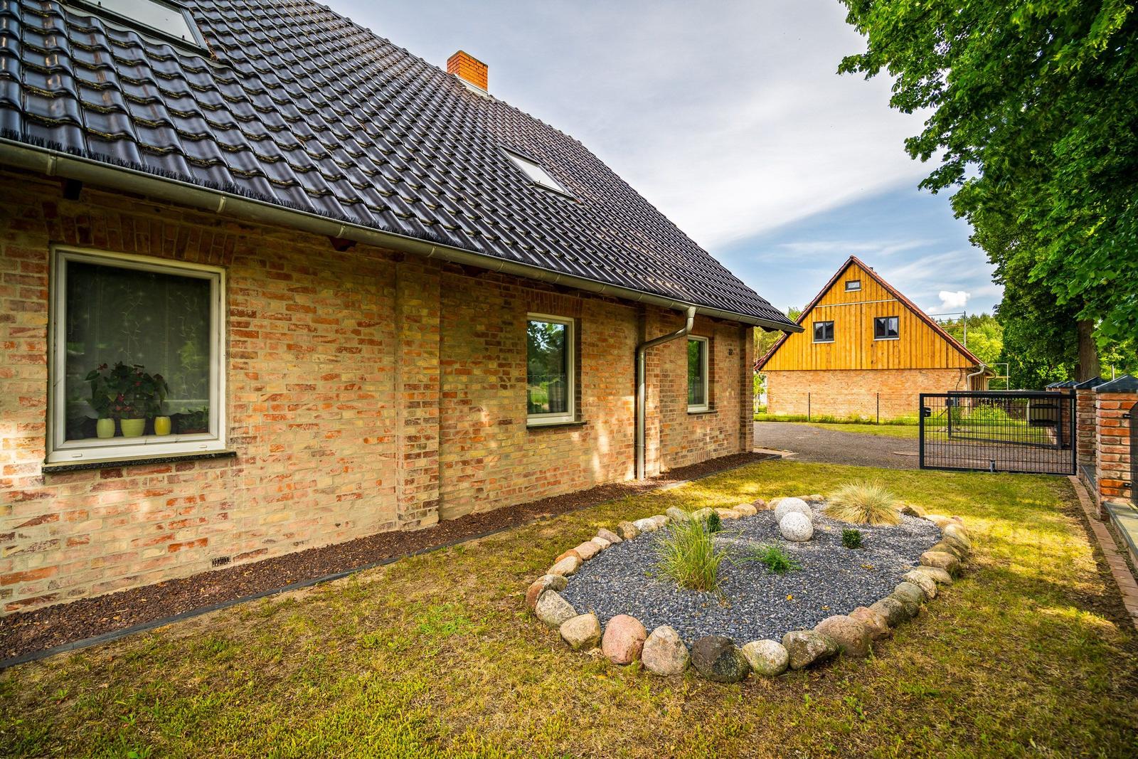 Ein Haus mit Backsteinfassade und Dachgauben. Vorgarten mit Steinbeet und Zaun.