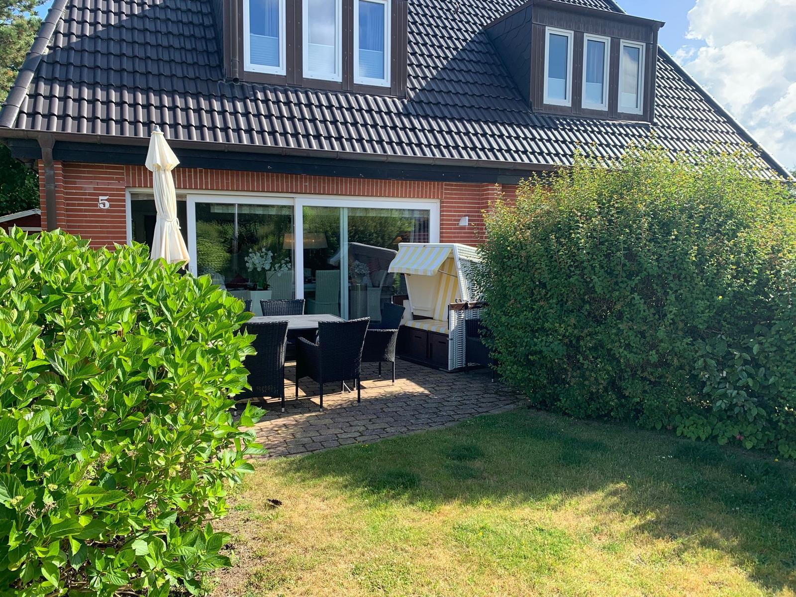 Haus mit Terrasse, Garten und Strandkorb. Große Fensterfront zur Aussicht.