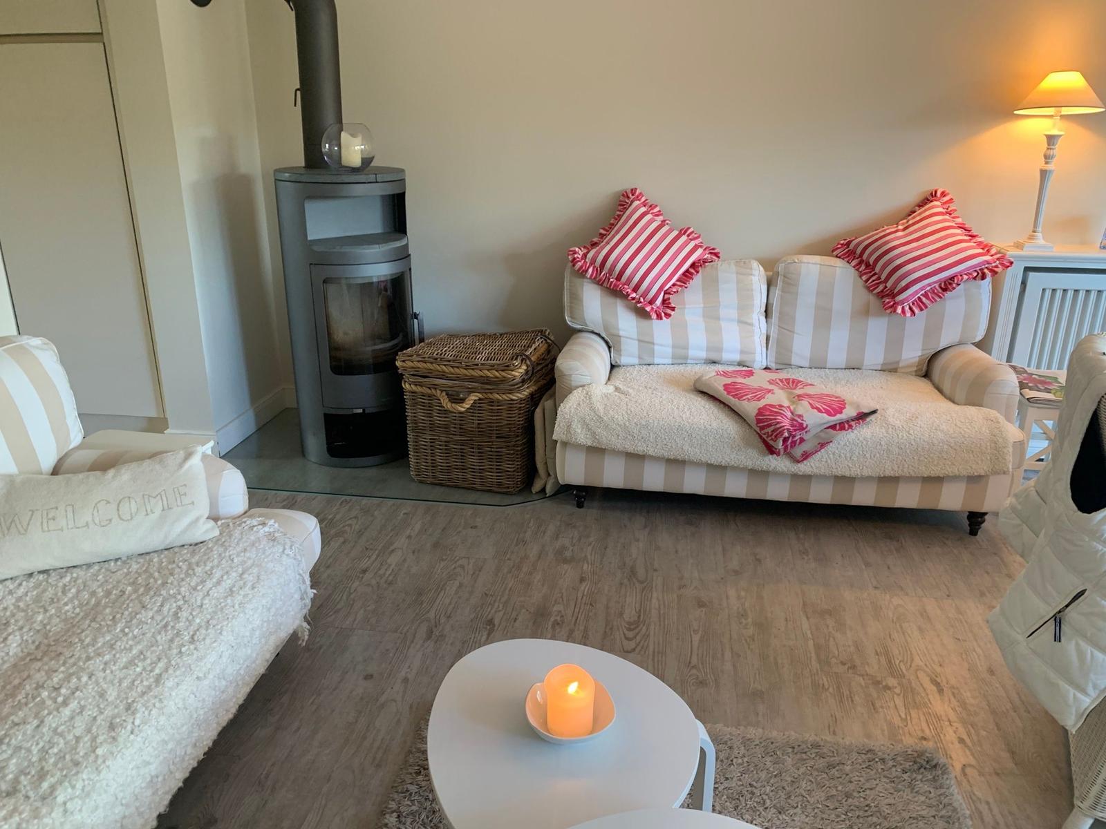 Wohnzimmer mit Sofa, Kaminofen und Beleuchtung.