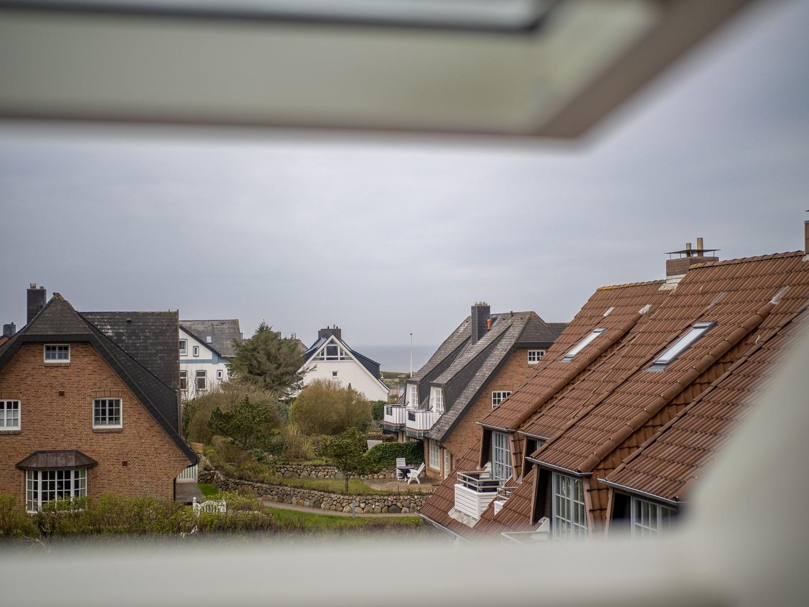 Ansicht auf Dächer und Gärten von Ferienhaus. Blick über Steinmauern und Bäume.
