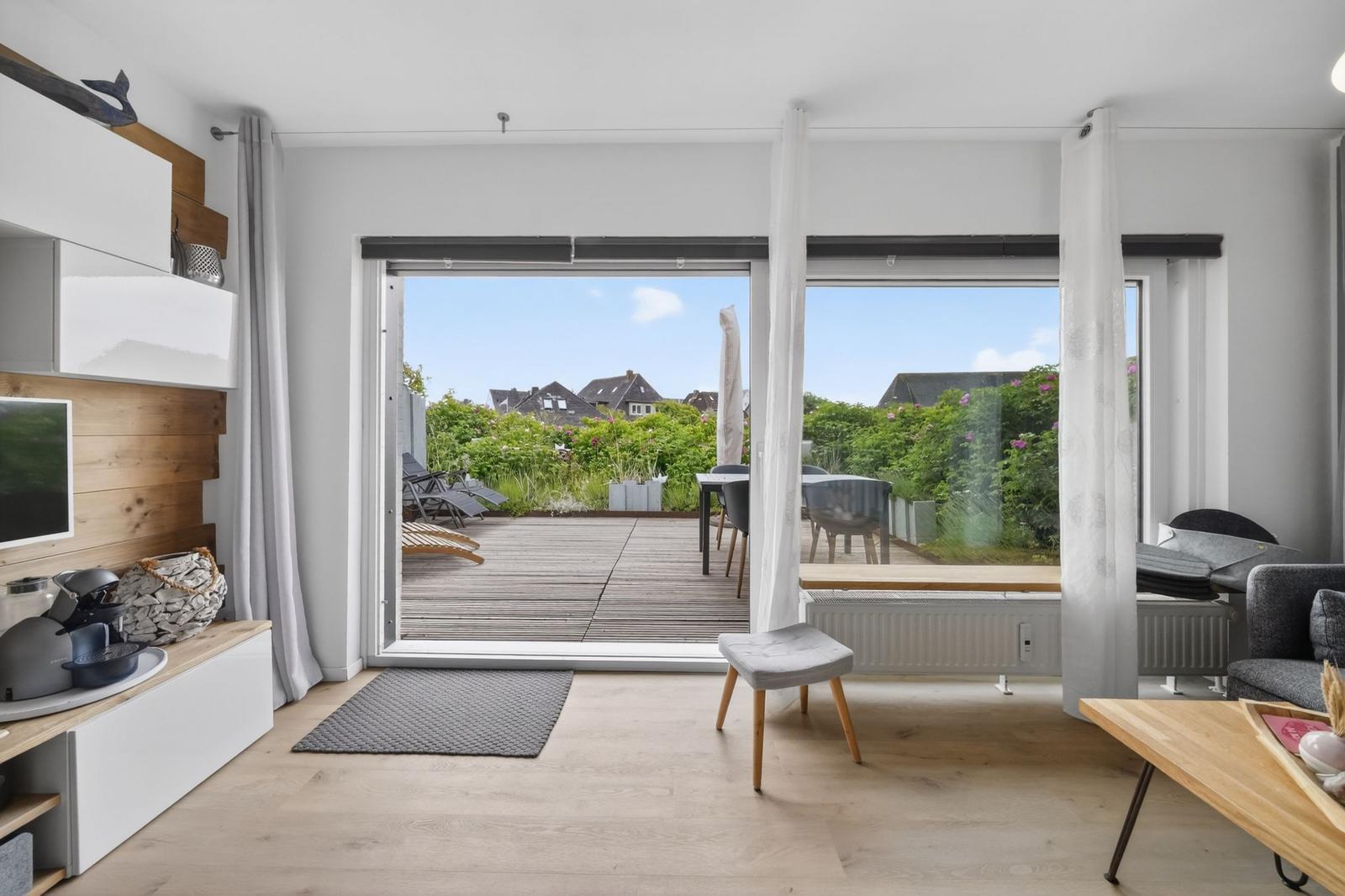 Wohnbereich mit Blick auf Terrasse und Garten. Moderne Einrichtung und helles Interieur.