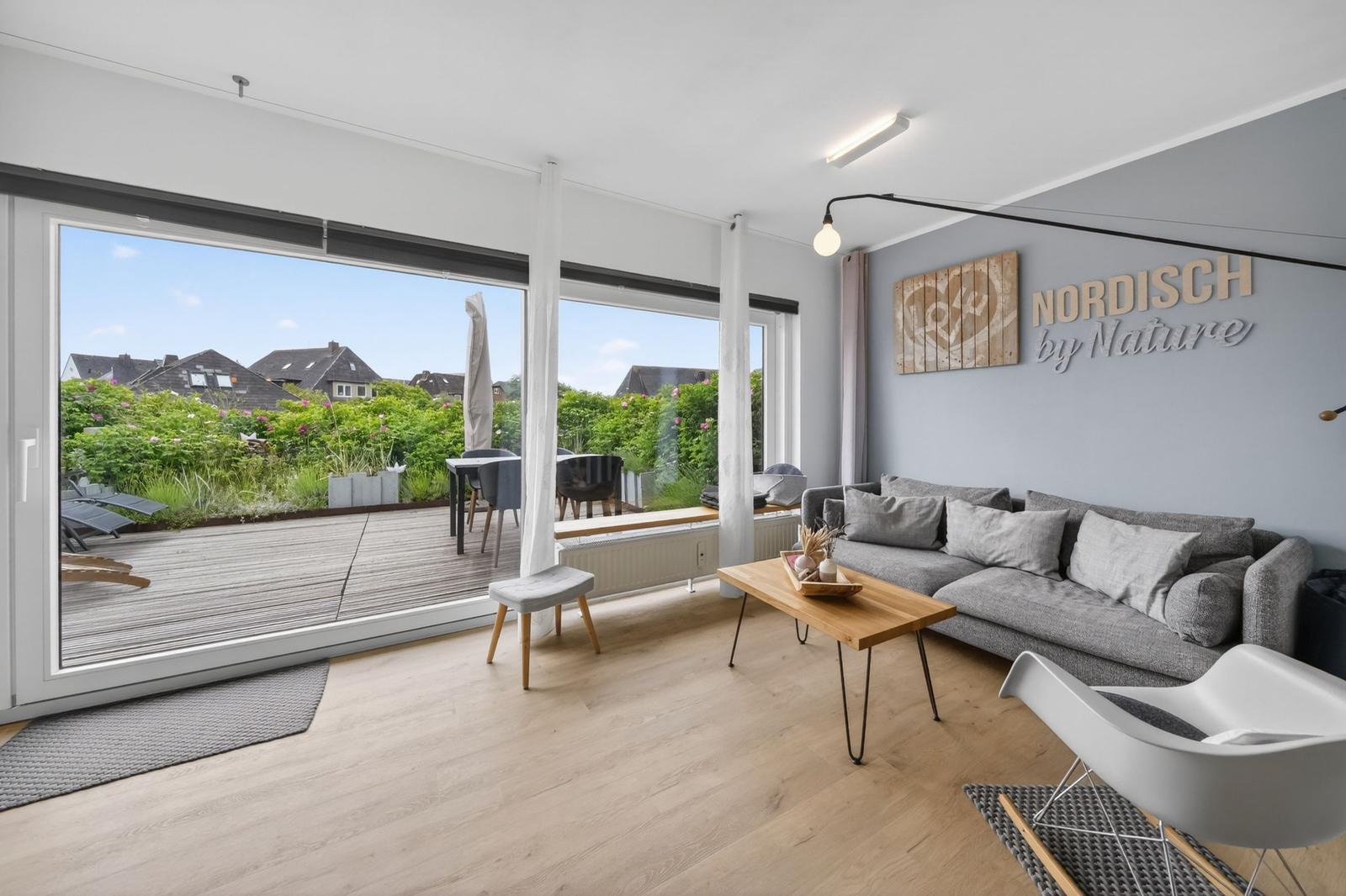 Wohnzimmer mit Sofa, Tisch und Blick auf Terrasse