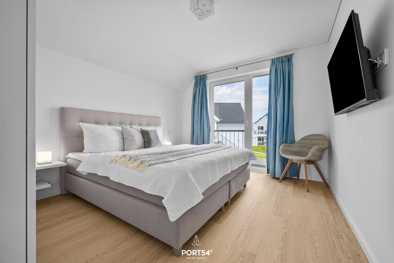 Schlafzimmer mit Doppelbett, TV und Balkonansicht.