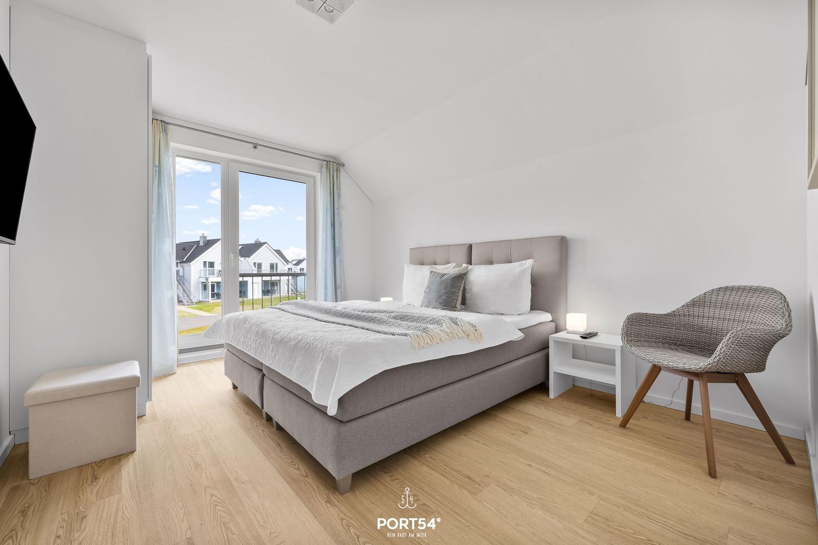 Schlafzimmer mit Bett, Stuhl und Fenster zur Aussicht.