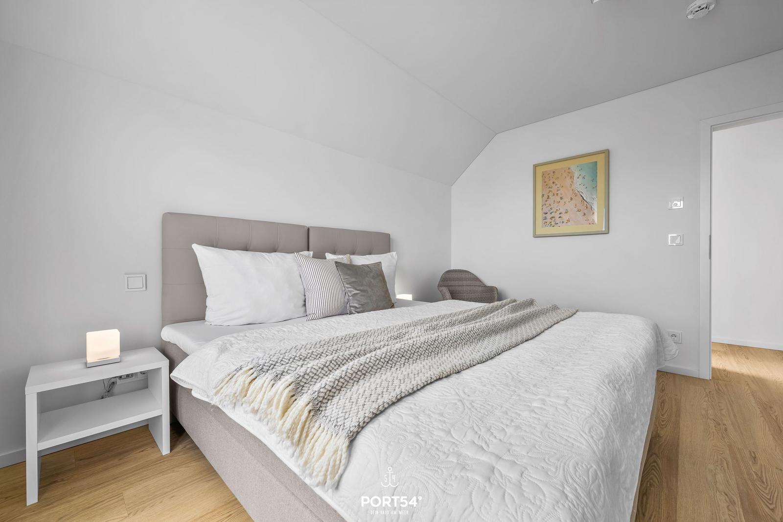 Schlafzimmer mit Bett, Nachttisch und Bild an der Wand.