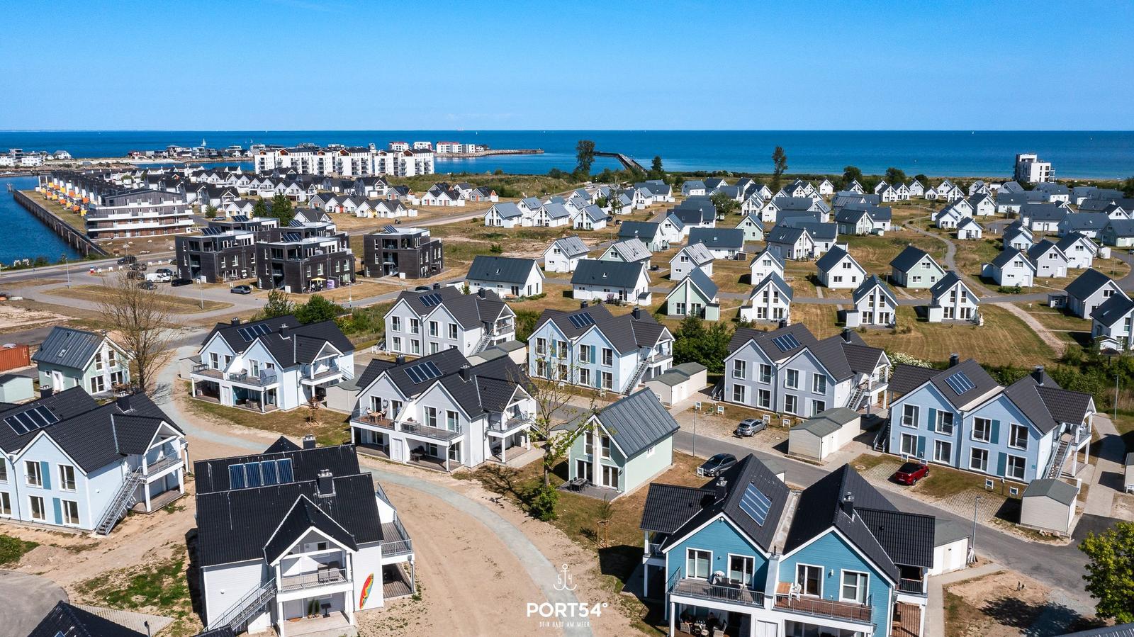 Aerial view of modern vacation homes near the sea with solar panels on roofs.