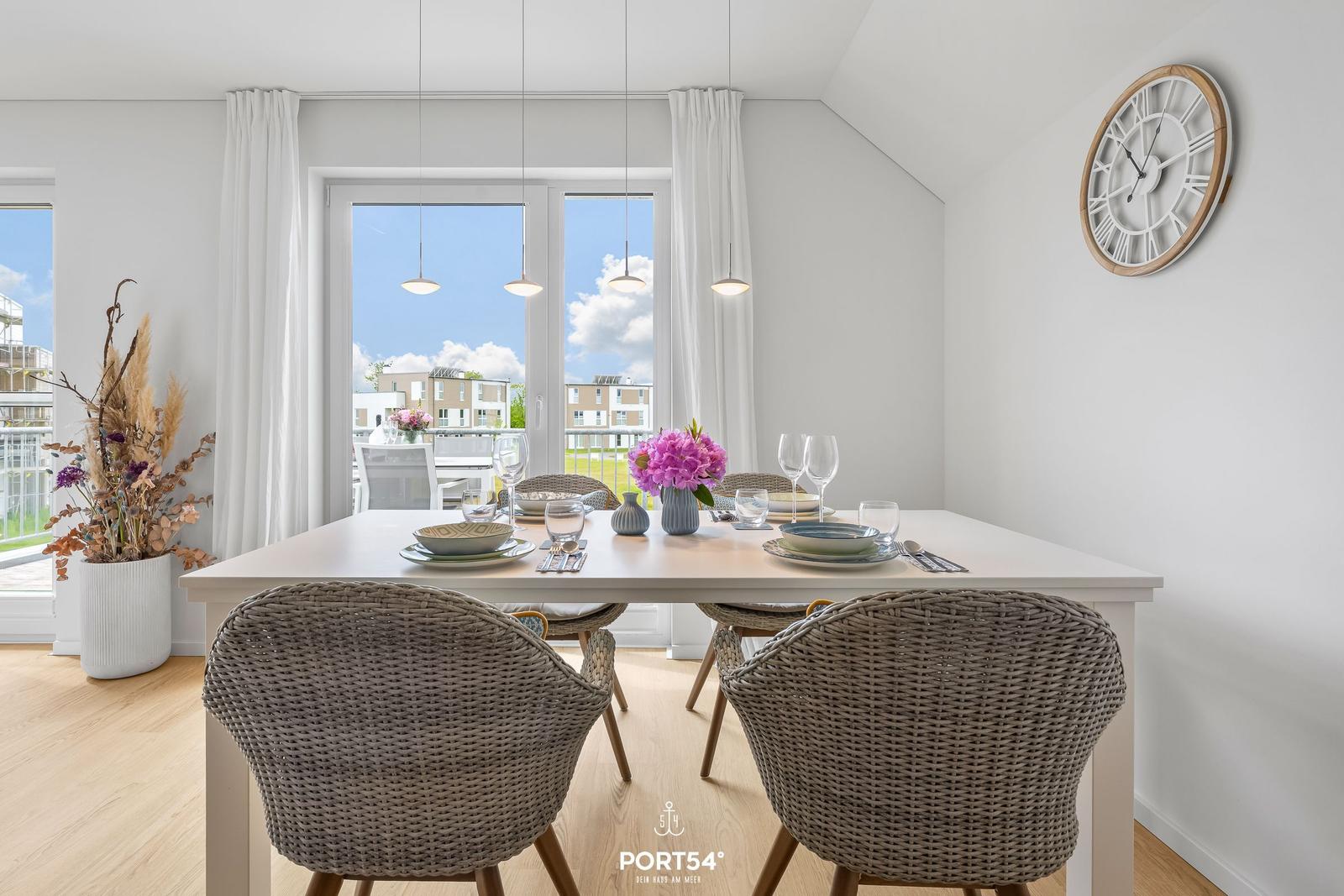 Esstisch mit Stühlen, Fenster und Wanduhr im Esszimmer.